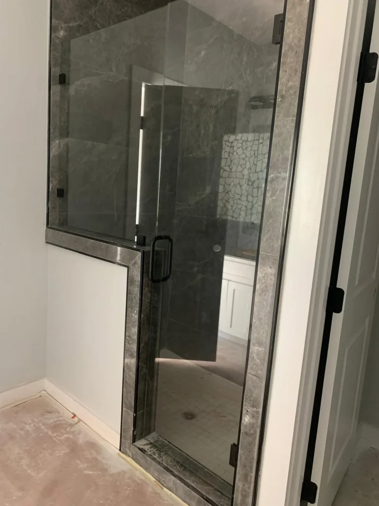 Frameless glass shower enclosure with black hardware installed by USA GLASS