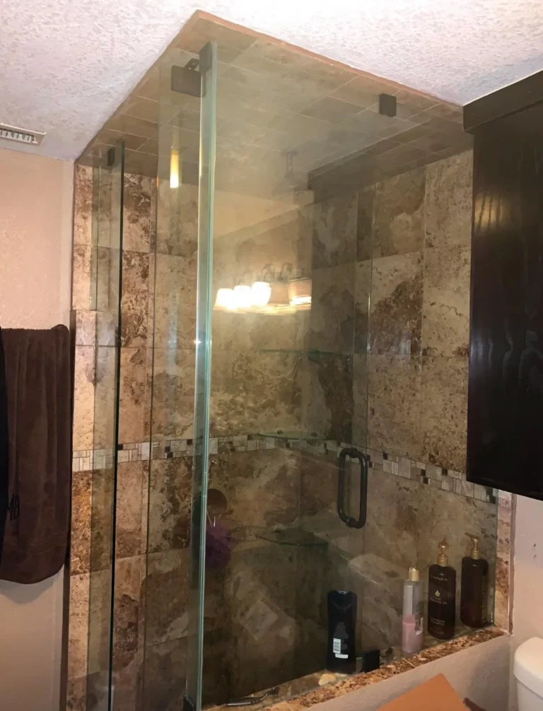 Clear glass shower enclosure against stone tile installed by USA GLASS